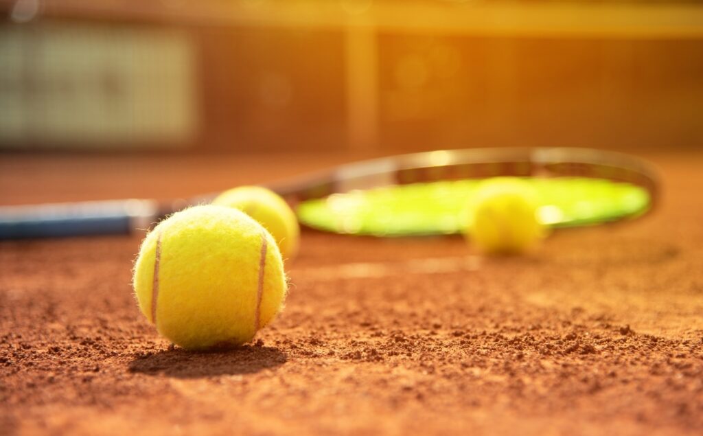 クレーコートに置かれたテニスボールとラケット