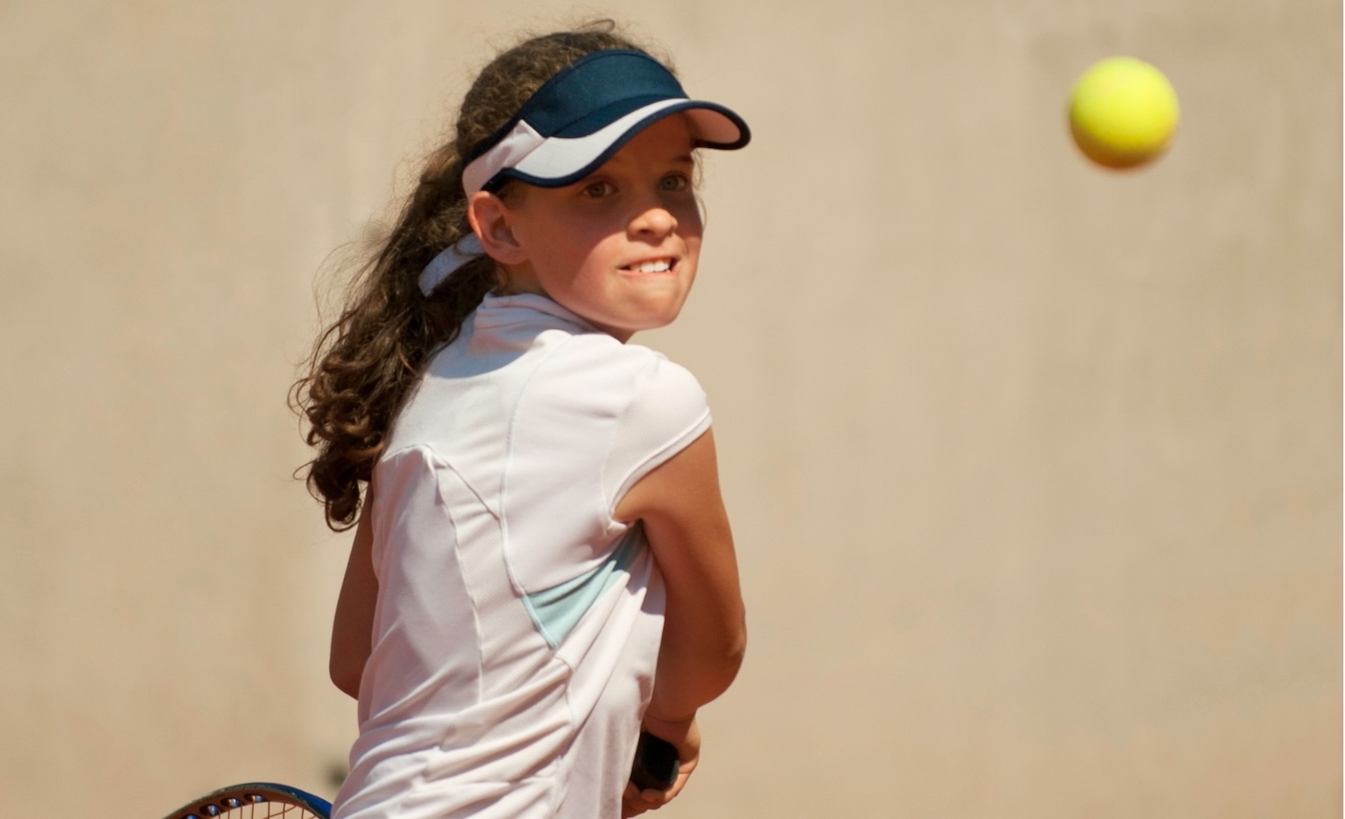 テニスに励む女子ジュニアテニスプレーヤー