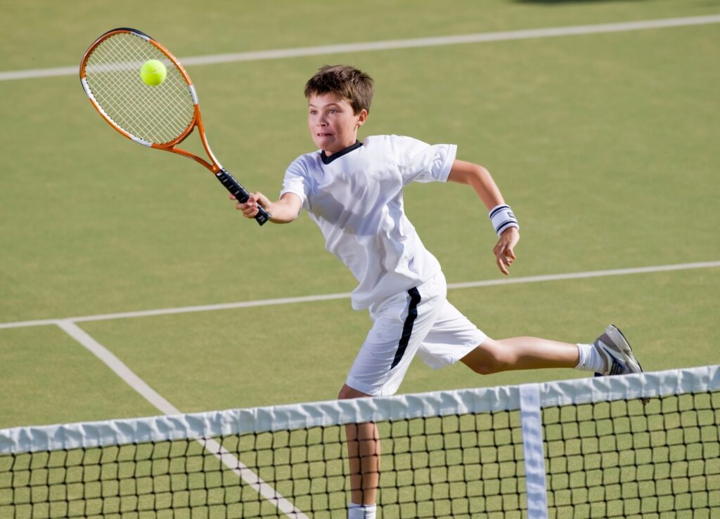 ボレーを打つ男子ジュニアテニスプレーヤー