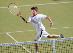 ボレーを打つ男子ジュニアテニスプレーヤー