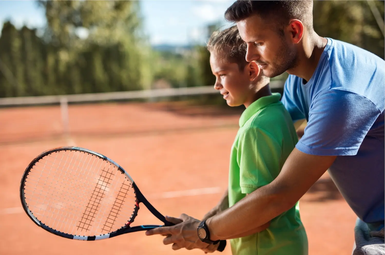 コーチに指導を受けるジュニアテニスプレーヤー